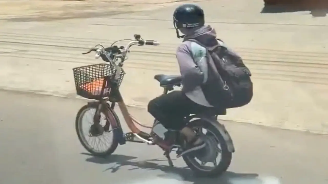 Nam sinh đi xe đạp điện buông hai tay trên quốc lộ